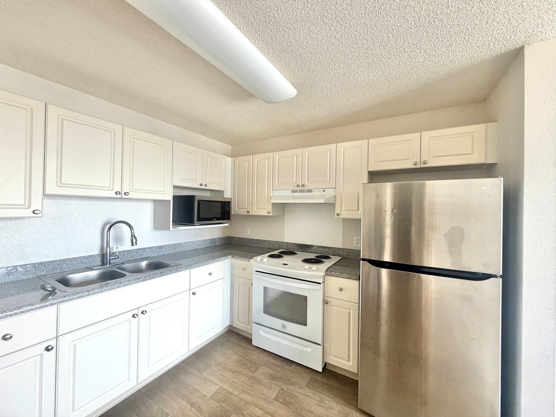 A kitchen with white cabinets and a stainless steel refrigerator.